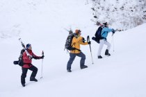 Three Chinese skiers hiking in snow-capped mountains — Stock Photo
