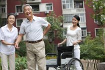 Senior chinesischer Mann mit Rückenschmerzen steht mit Frauen auf der Straße — Stockfoto
