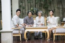 Chinese family sitting with tea and looking in camera — Stock Photo