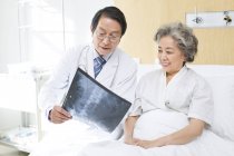Medico cinese che mostra l'immagine a raggi X al paziente — Foto stock