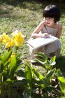 Niña china dibujando flores amarillas en el jardín - foto de stock