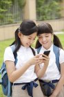 Chinesische Schülerinnen benutzen Smartphone auf dem Schulhof — Stockfoto