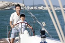 Chinese father and son sailing on yacht in bay — Stock Photo