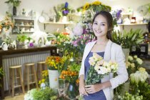 Chinesin steht mit Blumenstrauß im Geschäft — Stockfoto