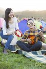 Pareja china tocando instrumentos musicales en camping - foto de stock