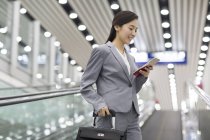 Chinesische Geschäftsfrau benutzt Smartphone auf Rolltreppe — Stockfoto