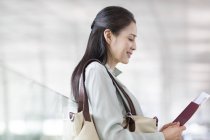 Chinese woman waiting at airport with ticket — Stock Photo