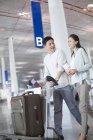 Pareja china madura caminando en el aeropuerto con la maleta - foto de stock
