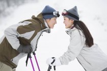 Couple chinois debout face à face avec des bâtons de ski — Photo de stock