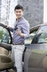 Hombre chino posando con llaves delante del coche - foto de stock