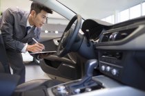 Mécanicien automobile chinois prenant des notes dans la voiture — Photo de stock