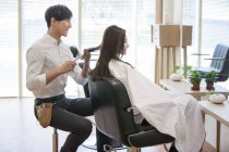Chinese barber cutting female customer hair — Stock Photo