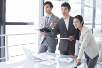 Chinese business people pointing at meeting in board room — Stock Photo