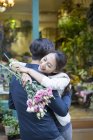 Femme chinoise embrassant petit ami avec des fleurs — Photo de stock