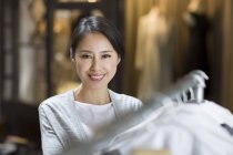 Зрелый владелец китайского бутика, стоящий у стойки с одеждой — стоковое фото