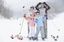 Familia china posando en estación de esquí con bastones de esquí - foto de stock