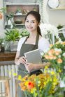 Китайский флорист держит цифровой планшет в магазине — стоковое фото