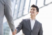 Chinese businessmen shaking hands on street — Stock Photo