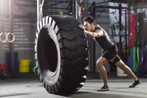 Chinois poussant gros pneu dans Crossfit gym — Photo de stock
