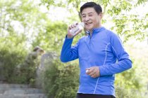 Зрелый китаец пьет воду после тренировки — стоковое фото