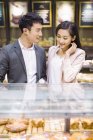 Chinese couple choosing pastry in bakery — Stock Photo