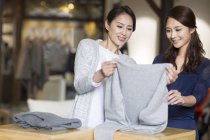 Mature Chinese boutique owner helping customer choosing clothes — Stock Photo