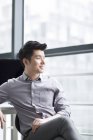 Китайський бізнесмен, дивлячись через вікно в офісі — стокове фото