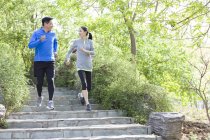 Mature chinese couple running on stairs in park — Stock Photo