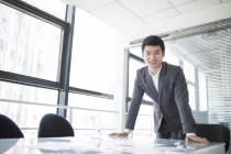 Китайський бізнесмен, спираючись на столі в офісі — стокове фото