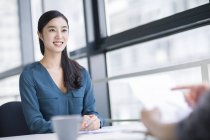 Chinesin sitzt bei Treffen im Büro — Stockfoto