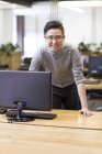 Cinese maschio IT lavoratore appoggiato sulla scrivania in ufficio — Foto stock