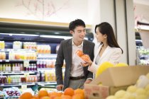 Pareja china comprando frutas en el supermercado - foto de stock