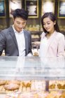 Chinese couple choosing pastry in bakery — Stock Photo