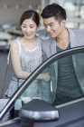 Китайська пара, дивлячись на автомобіль в автосалоні — стокове фото