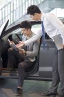 Distribuidor de coches chinos ayudando al cliente a elegir el coche en la sala de exposición - foto de stock