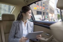 Chinese businesswoman using digital tablet in car — Stock Photo