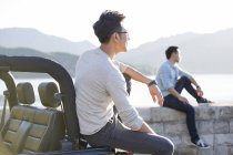 Chinese men sitting on lakeside and looking away — Stock Photo