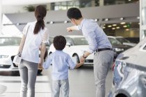 Family looking at cars in showroom, rear view — Stock Photo