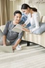 Chinese woman showing book to man with laptop at home — Stock Photo