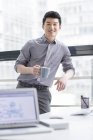 Chinese businessman holding cup of coffee in office — Stock Photo