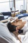 Chinesischer Geschäftsmann ruht sich auf Bett im Hotelzimmer aus — Stockfoto