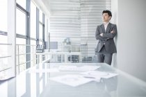 Китайский бизнесмен смотрит в окно в офисе — стоковое фото