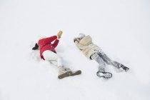 Enfants jouant et s'allongeant sur la neige — Photo de stock