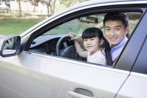 Padre chino sentado con su hija en el coche - foto de stock