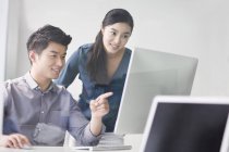 Chinese co-workers using computer in office — Stock Photo