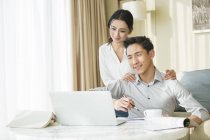Jovem casal chinês usando laptop em casa — Fotografia de Stock