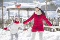 Chinese mother and daughter running in snow — Stock Photo