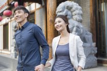 Chinesisches Paar hält Händchen vor Skulptur — Stockfoto