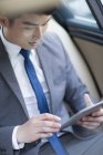 Homme d'affaires chinois utilisant une tablette numérique en voiture — Photo de stock