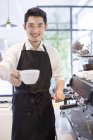 Barista chinois tenant une tasse de café — Photo de stock
